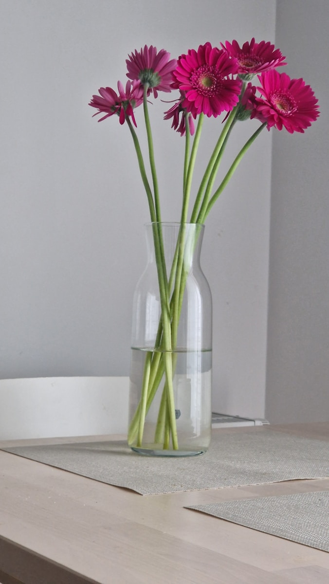 A glass vase filled with pink flowers on top of a table